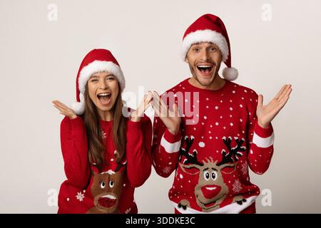 Heureux couple portant des pulls de Noël et des chapeaux célébrant la saison des fêtes ensemble Banque D'Images