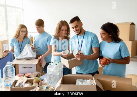 Jeunes bénévoles divers Trier les dons alimentaires dans des boîtes en carton pour une cause caritative Banque D'Images
