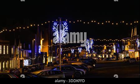 Vue nocturne de la rue décorée de Marlborough avec des lumières festives de vacances, des voitures garées et des bâtiments historiques sous un ciel sombre Banque D'Images