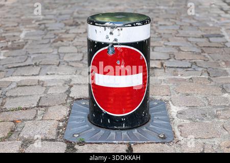 Borne noire et rouge avec une barre horizontale blanche, située sur un pavé Banque D'Images