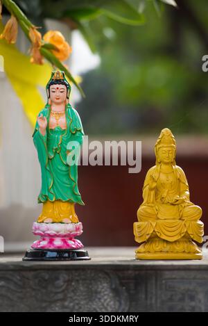 Deux statues de Bouddha, l'une verte et l'autre jaune, reposent sur un rebord de pierre. La statue verte est plus grande et a une pose plus proéminente, tandis que la stat jaune Banque D'Images
