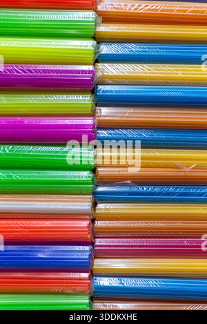 Gros plan abstrait de pailles à boire colorées empilées dans des aliments d'emballage en plastique Banque D'Images