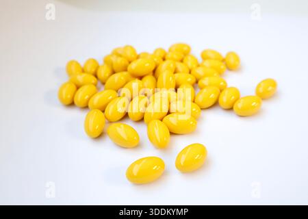 Capsules jaunes de softgel sur fond blanc, suppléments de vitamines Banque D'Images