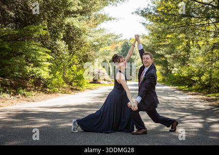 Couple en costume et robe frappent une pose animée à l'extérieur Banque D'Images