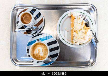 Deux tasses de café et une tranche de gâteau sur un plateau en métal dans un café au Portugal. Banque D'Images