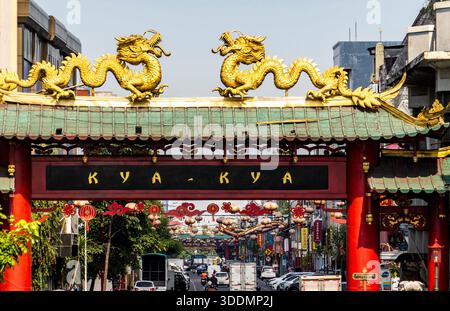 Sculptures de dragon doré sur une porte chinoise traditionnelle dans une rue animée de la ville. Banque D'Images