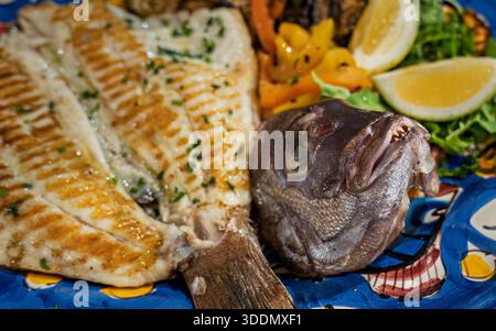Filet de dorade et tête de dorade, servi grillé sur une assiette avec légumes et quartiers de citron dans un restaurant à Amalfi, Campanie, Italie Banque D'Images