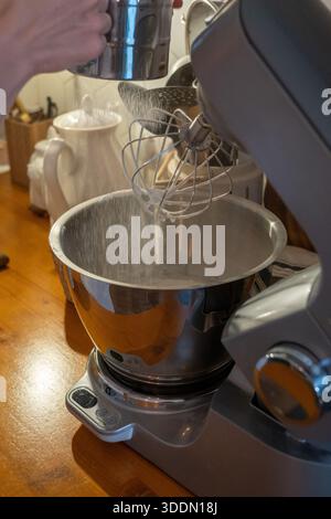 Les mains tamisent la farine dans le bol du mélangeur tout en préparant la pâte charlotte aux pommes sur le comptoir de cuisine en bois, capturant le moment de cuisson à la maison Banque D'Images