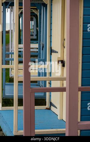 Image abstraite de la vue à travers l'avant d'une rangée ou d'une terrasse de cabanes de plage traditionnelles en bois peintes de couleurs vives. Banque D'Images