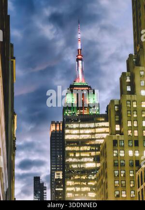 L'Empire State Building est éclairé dans les couleurs colorées, rouges et vertes de Noël par une froide soirée de décembre 2025, New York City, États-Unis Banque D'Images