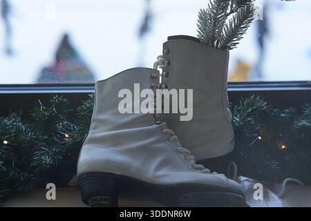 Paire de patins à glace blancs vintage utilisés comme décoration d'hiver parmi guirlandes festives.Budapest, Hongrie Banque D'Images