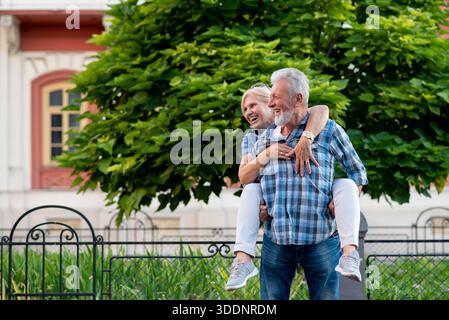 Heureux couple senior ayant du plaisir et profitant d'une promenade en plein air de piggyback Banque D'Images