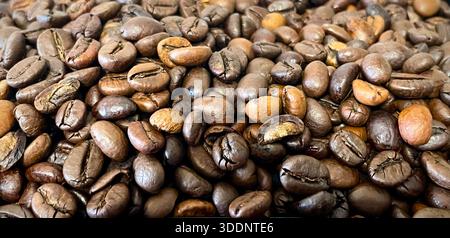 Gros plan de grains de café torréfiés avec des tons bruns riches et une texture naturelle, fond plein cadre Banque D'Images