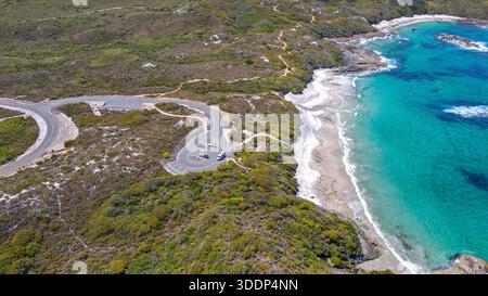 Découvrez un littoral à couper le souffle avec une plage sereine, une route sinueuse et une nature vibrante, parfait pour les loisirs en plein air. Banque D'Images
