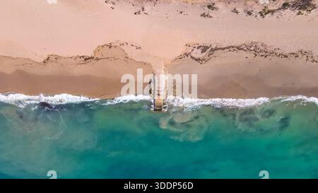 Une vue aérienne met en valeur une plage tranquille où les vagues douces rencontrent l'océan. La scène met en valeur la beauté de la nature et des paysages côtiers. Banque D'Images