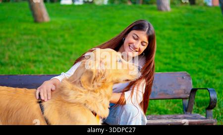 Femme caressant le chien Golden retriever sur le banc du parc Banque D'Images
