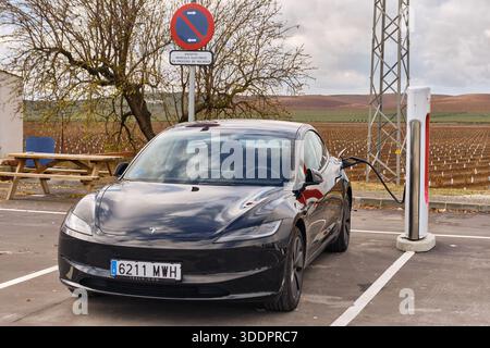Une Tesla Model 3 noire se charge au Supercharger d'une station-service Repsol dans le sud de l'Espagne. Cette image présente l'infrastructure de recharge de véhicules électriques Banque D'Images