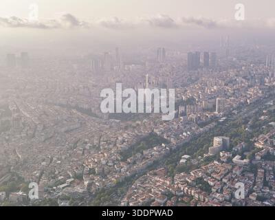 Photographie aérienne capturant un paysage urbain tentaculaire avec des bâtiments densément peuplés et d'imposants gratte-ciel sous un ciel brumeux, évoquant une sensation de ville Banque D'Images