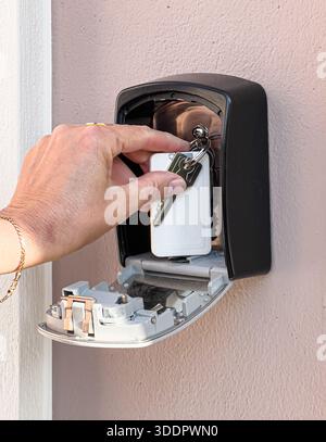 Placer les clés à la main à l'intérieur d'un coffre-fort à clé à combinaison monté sur un mur extérieur Banque D'Images