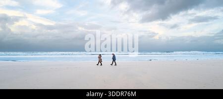 Une image panoramique d'un couple mûr marchant sur Fistral Beach à Newquay sur la côte nord de Cornouailles au Royaume-Uni. Banque D'Images