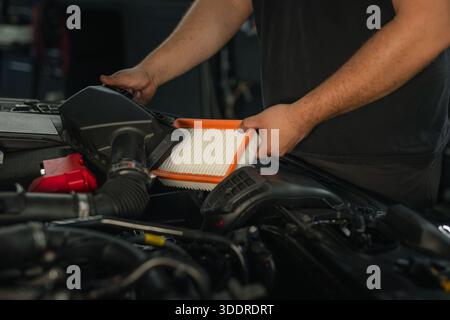 Mains d'un mécanicien remplaçant un filtre de voiture lors d'un service professionnel d'entretien du moteur. Banque D'Images