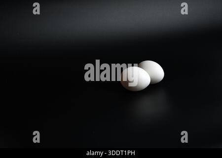 Concept de petit déjeuner minimaliste avec deux œufs blancs sur une petite soucoupe, lumière haute et basse. Banque D'Images