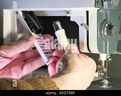 Ajustement d'une machine à coudre Vintage gros plan ; gros plan de la main d'une personne installant ou réparant une machine à coudre plus ancienne et classique. Concentrez-vous sur le m Banque D'Images