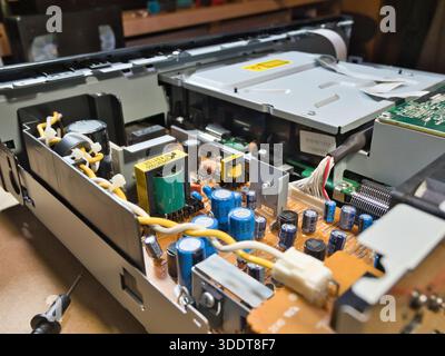 Test manuel de la carte électronique avec multimètre ; gros plan des mains d'un technicien à l'aide d'un multimètre pour diagnostiquer ou réparer un circuit électronique complexe Banque D'Images