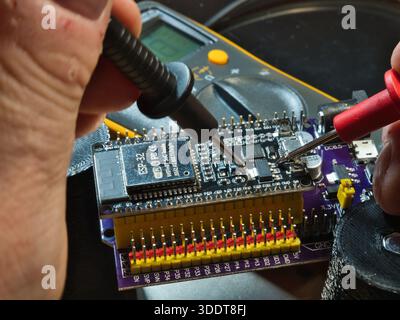 Test par ingénieur de la carte de microcontrôleur. ; Gros plan d'un ingénieur testant la tension sur une carte de développement de microcontrôleur (PCB) moderne à l'aide d'un m numérique Banque D'Images