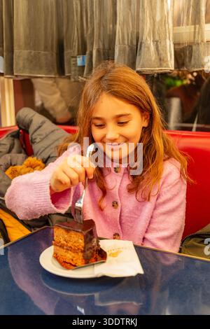 Fille mangeant Sachertorte , gâteau Sacher au Palmenhaus, Vienne, Autriche. Banque D'Images
