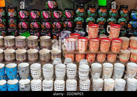 Collection colorée et diversifiée de tasses, tasses et pots en céramique fabriqués à la main disposés pour la vente à un étal de marché Banque D'Images