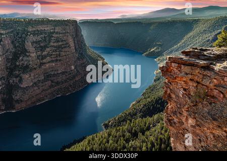 Des couches rocheuses sédimentaires rouges, oranges et grises à bandes vives s'élèvent au-dessus des eaux bleues profondes du réservoir Flaming gorge le long de la frontière entre l'Utah et le Wyoming. Banque D'Images