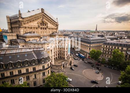 Coucher de soleil sur Paris depuis le toit des Galeries Lafayette, avec le dôme du Palais Garnier et la Tour Eiffel silhouette sur un ciel doré. Banque D'Images