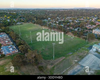 Une perspective de drone aérien capture de vastes terrains de sport verts équipés de plusieurs poteaux de but, bordés par des bâtiments résidentiels et dense subur Banque D'Images