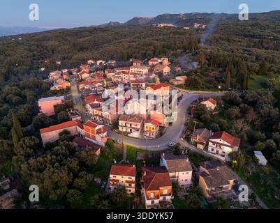 Large vue aérienne drone du paysage du village de xanthates à Corfou en Grèce entouré de cyprès et d'oliviers au coucher du soleil Banque D'Images