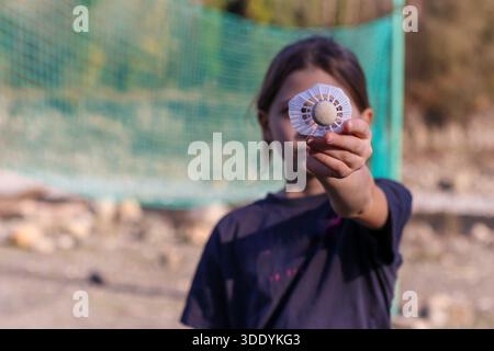 Plan intime se concentrant sur les doigts d'un enfant présentant un volant, avec filet extérieur flou et paysage d'automne en arrière-plan. Banque D'Images