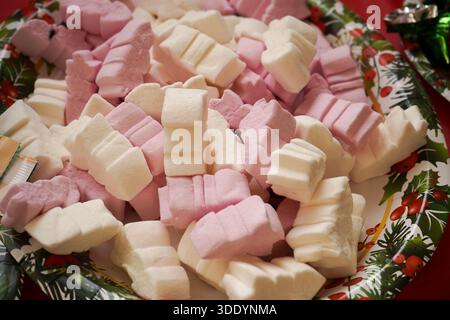 Bonbons à la guimauve moelleux roses et blancs servis sur une assiette de fête en papier. Friandises sucrées pour une fête de Noël ou une fête d'enfants. Banque D'Images