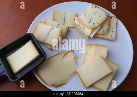 Fromage raclette suisse traditionnel servi avec des pommes de terre et des viandes séchées Banque D'Images