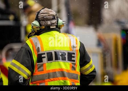 Vue rapprochée de derrière un pompier en équipement de protection complet, montrant clairement le texte réfléchissant « INCENDIE » ou l'insigne du service au dos de la Banque D'Images
