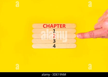 Symbole temps jusqu'au chapitre 2. Concept Word Chapitre 1 2 3 4 sur de beaux bâtons de bois. Main d'homme d'affaires. Beau fond jaune. Planification des activités Banque D'Images