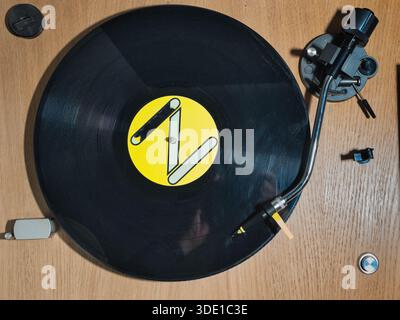 Platine Vintage avec disque vinyle noir ; vue de dessus d'une platine vinyle classique en bois tournant un disque vinyle noir avec une étiquette jaune vif. Captu Banque D'Images