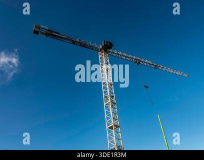 Une grue à tour blanche par construction de murs contre un ciel bleu clair. Symbole du développement urbain moderne de Dublin et de la transformation en cours du centre-ville Banque D'Images