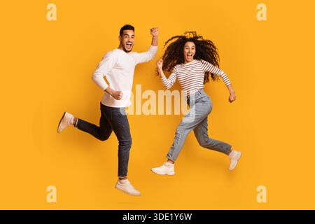 Un couple arabe débord de joie et enthousiaste qui saute dans l'air sur fond jaune Banque D'Images