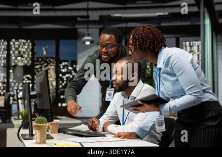 Groupe d'employés noirs faisant un travail d'équipe sur une tâche importante tard dans la nuit, collaborant à l'élaboration d'une nouvelle stratégie de développement après les heures de travail. Examiner les informations pour améliorer l'efficacité. Banque D'Images