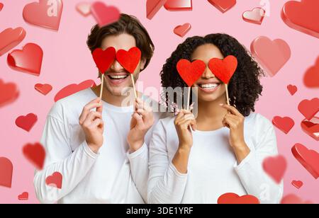 Happy couple couvre les yeux avec les coeurs pour un moment amusant dans le cadre Studio Banque D'Images