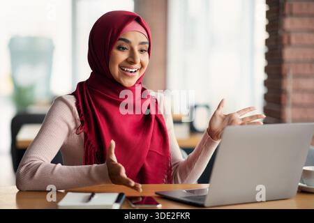 Femme musulmane émotive ayant un entretien d'emploi en ligne, à l'aide d'un ordinateur portable Banque D'Images
