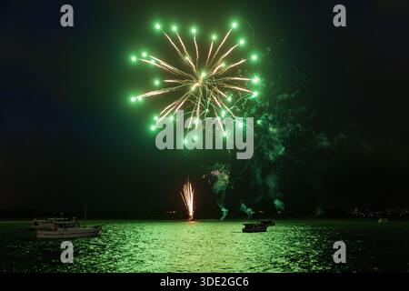 Un feu d'artifice vert « chrysanthème » éclate au-dessus des bateaux dans un port pendant les fêtes du nouvel an. Tauranga, Nouvelle-Zélande Banque D'Images