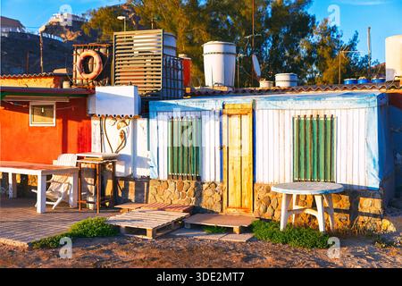 Vue d'une habitation colorée et de fortune avec des meubles de jardin et divers objets dispersés autour. La structure semble être petite, maison rustique dans le soleil, Banque D'Images