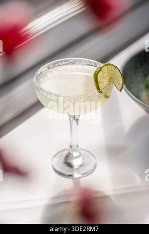 Cocktail margarita classique servi dans un verre traditionnel avec un bord salé et une garniture de citron vert frais. Boisson alcoolisée rafraîchissante. Banque D'Images