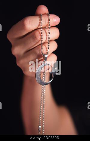 Femme tenant un pendentif en argent avec croissant de lune et symbole d'étoile. Concept de spiritualité pour le culte et les fêtes religieuses. Banque D'Images